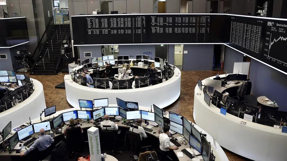 Traders at ring-shaped desks with banks of monitors under electronic price boards on the Frankfurt Stock Exchange floor