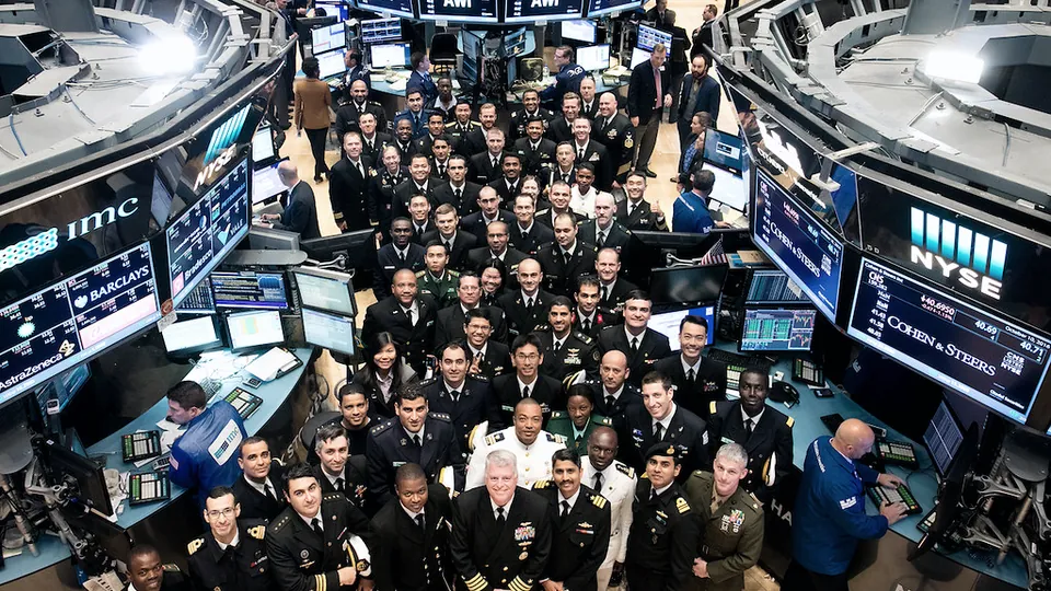 A crowded stock exchange floor with traders around banks of price screens
