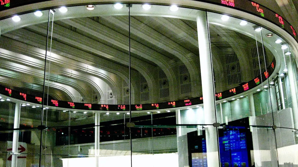 A circular electronic ticker ring showing stock prices above an exchange floor