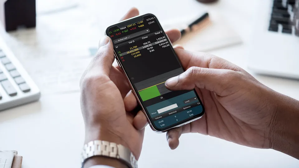 Hands holding a phone with a stock trading app open on the screen